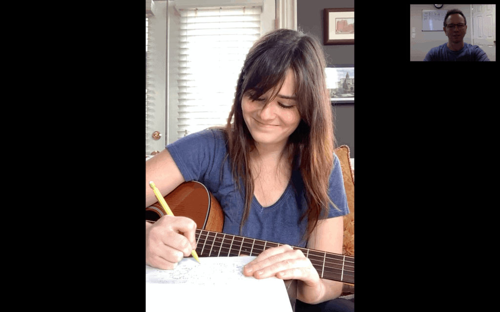 Female college student writing lyrics to her song in online music lesson with Shane Lamb.