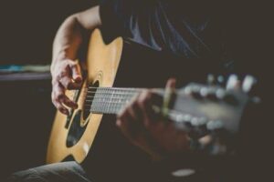 hands playing acoustic guitar.