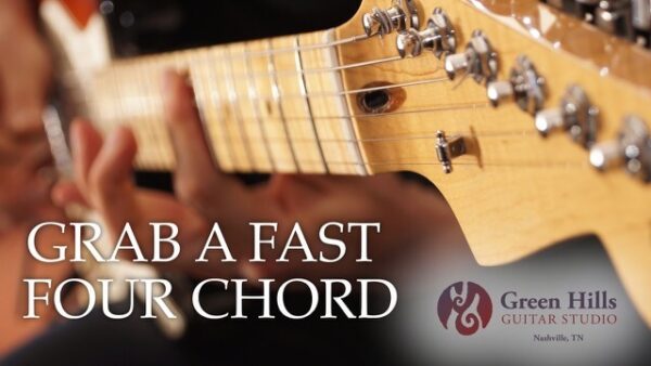 Left hand playing a barre chord on an electric guitar